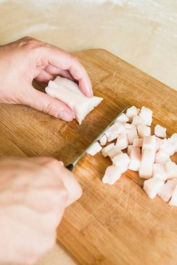 bir adam pişmemiş domuz yağı parçalar halinde keser.