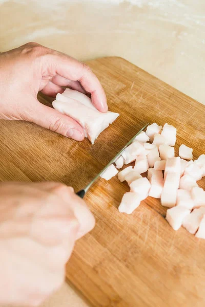 bir adam pişmemiş domuz yağı parçalar halinde keser.