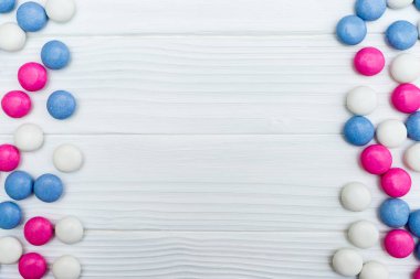 Beyaz ahşap arka plan üzerinde renkli nane kaplı şekerler doku çerçevesinden. Üstten Görünüm. Kopya alanı