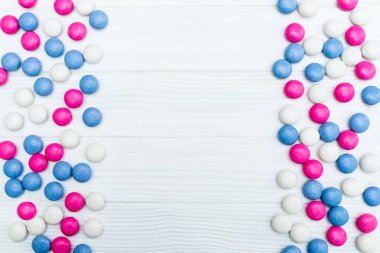 Beyaz ahşap arka plan üzerinde renkli nane kaplı şekerler doku çerçevesinden. Üstten Görünüm. Kopya alanı