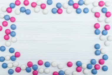 Beyaz ahşap arka plan üzerinde renkli nane kaplı şekerler doku çerçevesinden. Üstten Görünüm. Kopya alanı