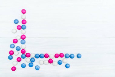 Beyaz ahşap arka plan üzerinde renkli nane kaplı şekerler doku çerçevesinden. Üstten Görünüm. Kopya alanı