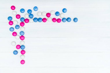 Beyaz ahşap arka plan üzerinde renkli nane kaplı şekerler doku çerçevesinden. Üstten Görünüm. Kopya alanı