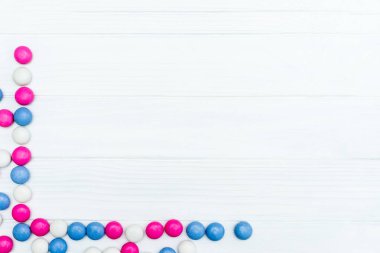 Beyaz ahşap arka plan üzerinde renkli nane kaplı şekerler doku çerçevesinden. Üstten Görünüm. Kopya alanı