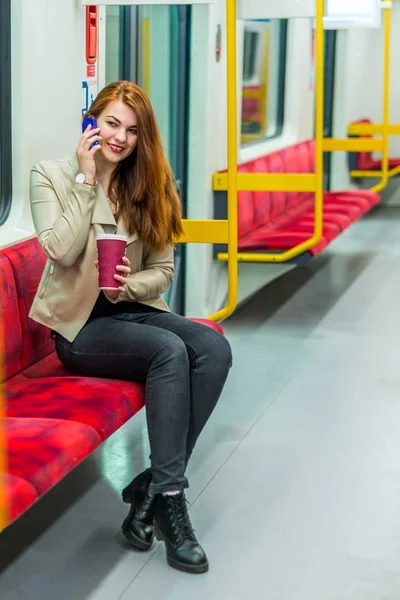 Kız boş bir metroyu içinde cep telefonuyla konuşuyor. Kız bir akıllı telefon ile metro bir arabada oturuyor