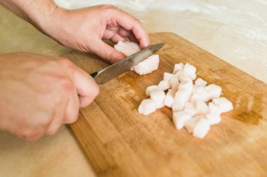 bir adam pişmemiş domuz yağı parçalar halinde keser.