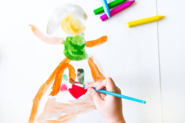 Çocuk bir boş kağıda beyaz akrilik boya ile bir fırçayla çiziyor. Çocuk suluboya ile çizim