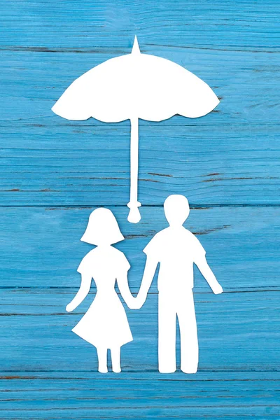 Бумажный силуэт мужчины и женщины, держащихся за руки под зонтиком — стоковое фото