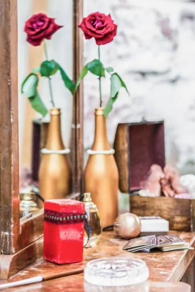上一张梳妆台和镀金的瓶子里的红玫瑰蜡烛 — 图库照片