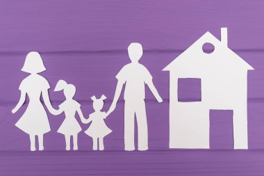 Erkek ve kadın evin yakınlarında iki kızla kağıt kesme siluetleri