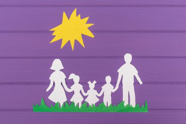 Güneşin altında çimlerin üzerine kağıt erkek ve iki kız ve erkek ile kadın siluetleri kesmek