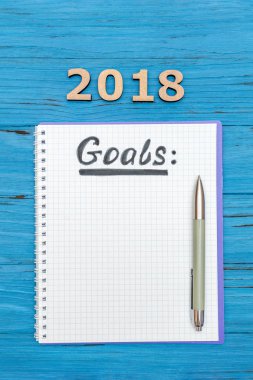 Defter bir kalem ve sayı 2018 mavi ahşap bir masa üzerine ile 2018 için yeni yıl gol ile
