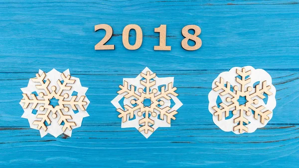 Los números 2018 y tres copos de nieve de madera en la mesa vieja de madera azul — Foto de Stock