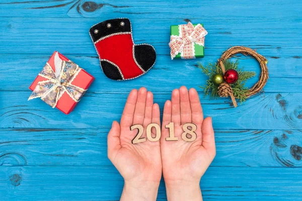 Γυναικεία χέρια εκμετάλλευσης αριθμούς 2018 κοντά κουτιά δώρων και το νέο έτος στολίδια στο μπλε παλιό τραπέζι — Φωτογραφία Αρχείου