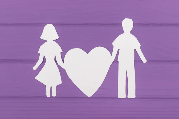 Paper silhouette of man and woman holds big heart — Stock Photo, Image