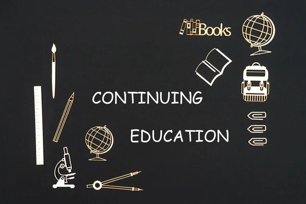 School supplies placed on black background with text continuing education — Stock Photo, Image