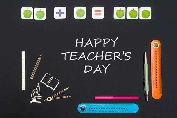 Irodaszer ellátás és a szöveg boldog tanárok nap a fekete háttér — Stock Fotó