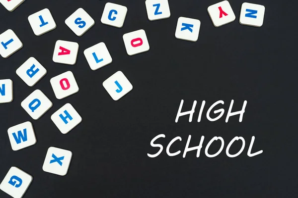 English colored square letters scattered on black background with text high school — Stock Photo, Image