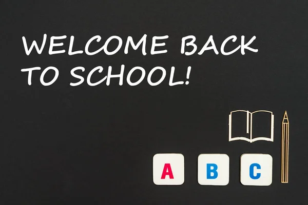 Letras cuadradas de color inglés dispersas sobre fondo negro con texto bienvenido de vuelta a la escuela — Foto de Stock