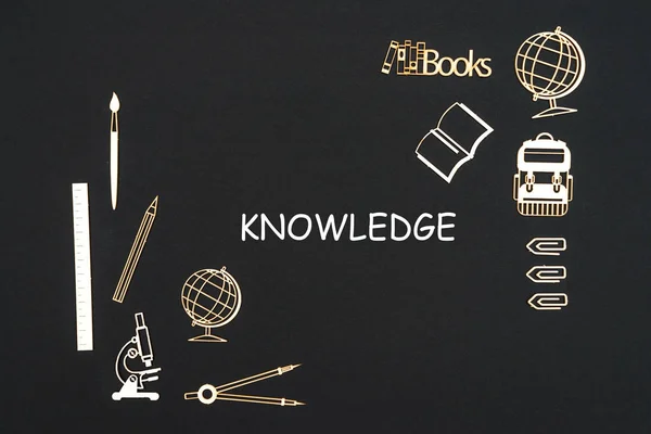 Schoolbenodigdheden geplaatst op zwarte achtergrond met kennis van de tekst — Stockfoto