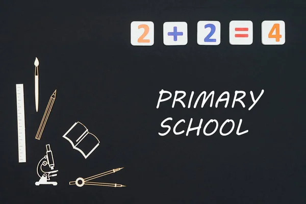 Schulmaterial auf schwarzem Hintergrund mit Text Grundschule platziert — Stockfoto