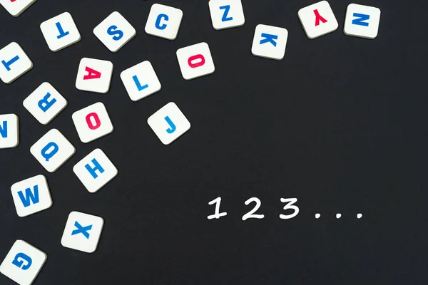 Letras cuadradas de color inglés dispersas sobre fondo negro con números 123 — Foto de Stock