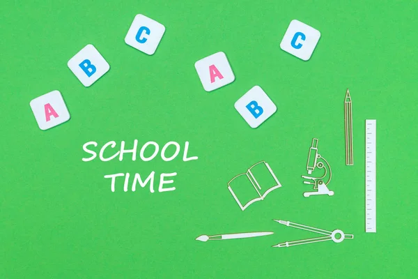 Texte heure de l'école, de dessus en bois minitures fournitures scolaires et abc lettres sur fond vert — Photo