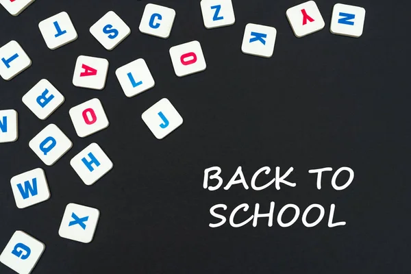 Letras cuadradas de color inglés dispersas sobre fondo negro con texto de vuelta a la escuela — Foto de Stock