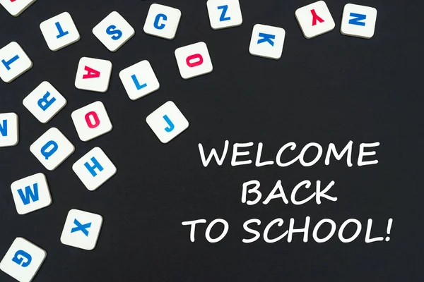 Letras cuadradas de color inglés dispersas sobre fondo negro con texto bienvenido de vuelta a la escuela — Foto de Stock