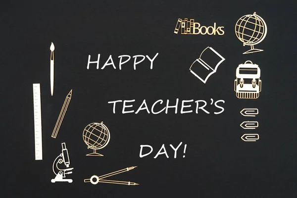 Iskolai felszerelés elhelyezett fekete háttér szöveg boldog Pedagógusnap — Stock Fotó