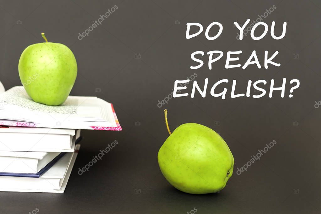 text do you speak english, two green apples, open books with concept