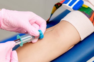 Hemşire, analizde kadın hastadan kan örneği alıyor..