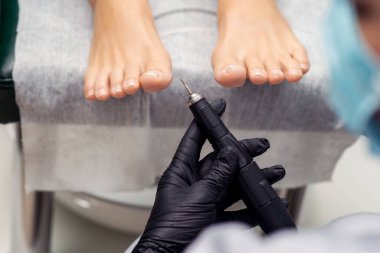 Pedikürcünün elinde ayak fonun pedikürü için elektrik makinesi var, kapat..