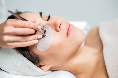 Kirpik uzatma işlemi gören kadının yüzünü kapat.