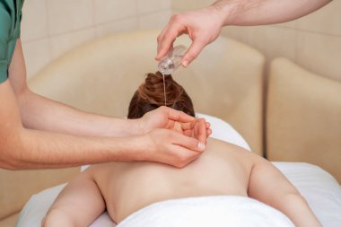Masaj terapisti, kadına sırt masajından önce ellere yağ sürüyor..