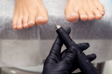 Profesyonel pedikür teknisyeni ayak soyma tıbbi pedikür prosedürü için özel elektrikli makine tutuyor..