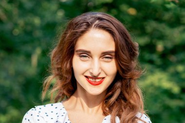 Yaz doğasının yeşil arka planında gülümseyen güzel bir kadının portresi..