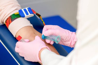 Hemşire, analizde kadın hastadan kan örneği alıyor..