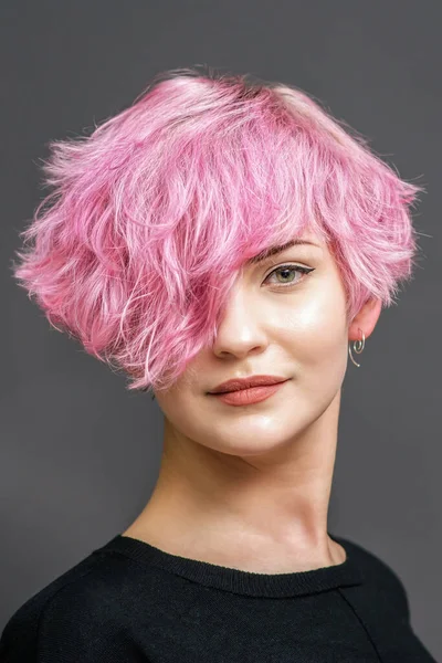 若いです女性の肖像とともに新しい短いピンクの髪型上の灰色の背景 — ストック写真