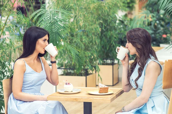 两名年轻妇女正在室外咖啡馆喝咖啡或喝茶 两个漂亮的女朋友在咖啡店喝咖啡 友谊概念 — 图库照片