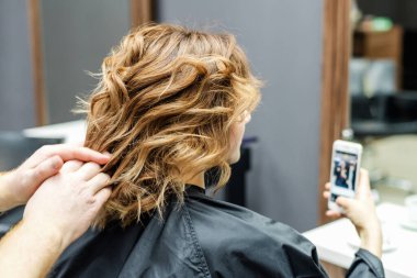 Kuaför kuafördeki kadın saç stilini kontrol ediyor..