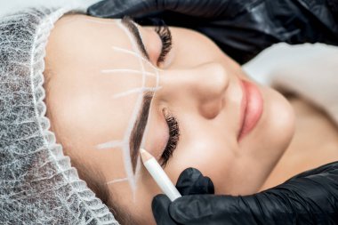 Kalıcı makyaj yaparken, yonglu kadının kaşlarında kalem olan bir marka..