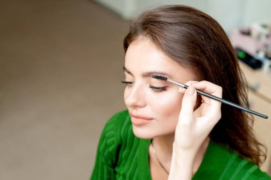 Makyaj sanatçısı kaşlarını kaş fırçası araç kopyalama alanı ile tarıyor.