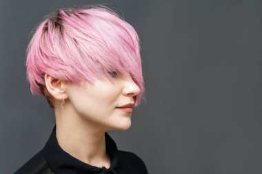 Modern kısa pembe saç stiline sahip yetişkin bir kızın portresi ve gri arka planda fotokopi alanı olan kapalı gözler..