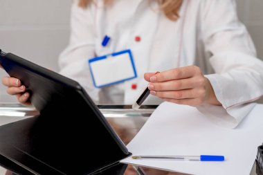 Hemşire kan testi tüpünü tablet cihazına kan örneği yazarken tutuyor..