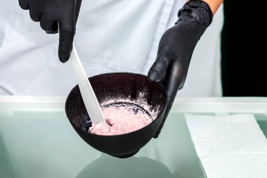 Eller siyah kasede aljinat maskesini hazırlıyor..