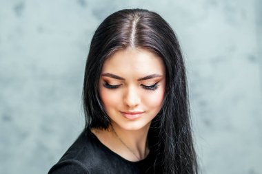 Uzun kirpikleri ve güzel makyajı var. Gri arka planda, fotokopi alanı olan güzel bir kadın..