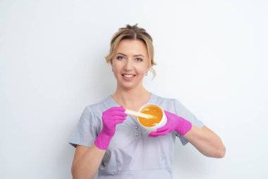 Güzellik uzmanı, beyaz arkaplanda kopyalama alanı olan balmumu dolu kavanozu gösteriyor.