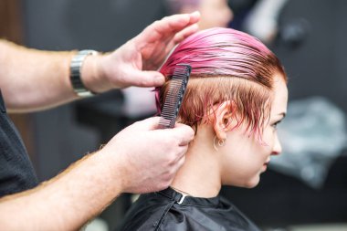 Güzellik salonunda kuaför saçını tarıyor..