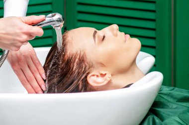 Kadın kuaförde lavaboda saçlarını yıkıyor..